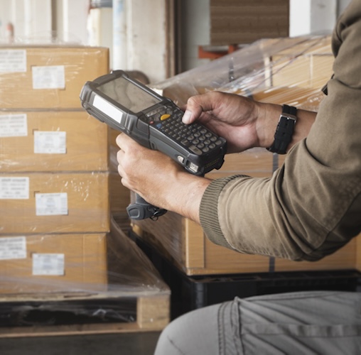 3PL Warehouse worker holding barcode scanner taking inventory near New York City.