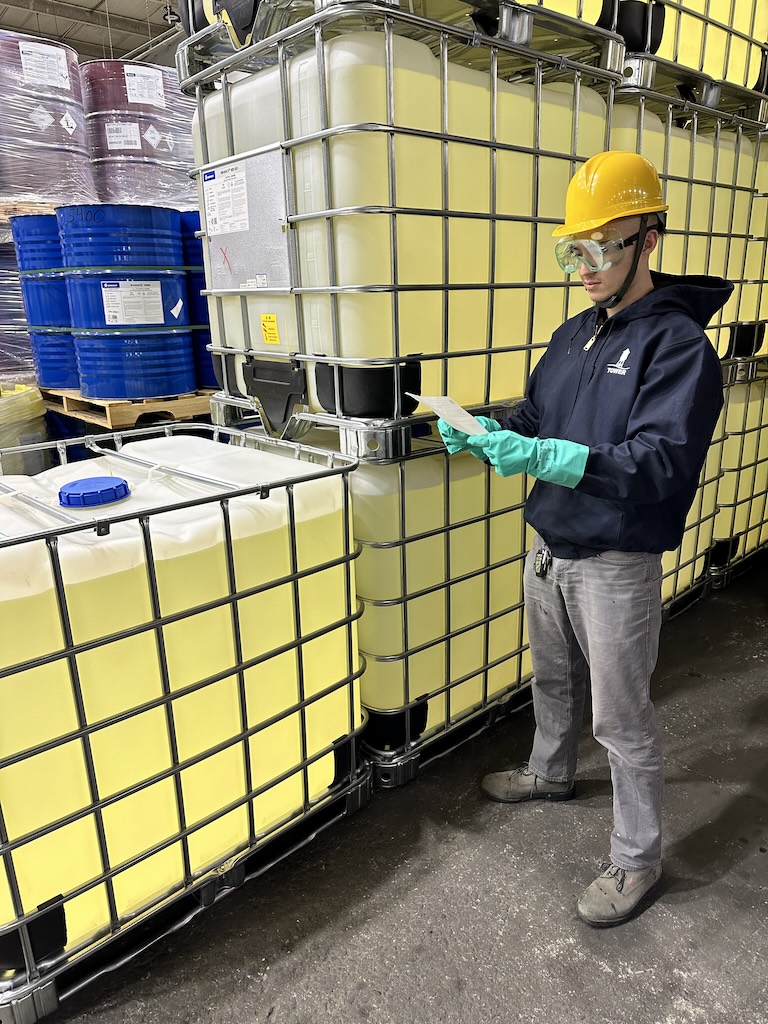 Worker in safety gear inspecting hazardous materials at a Tower Logistics facility in New Jersey, ensuring compliance and 3pl warehouse safety standards