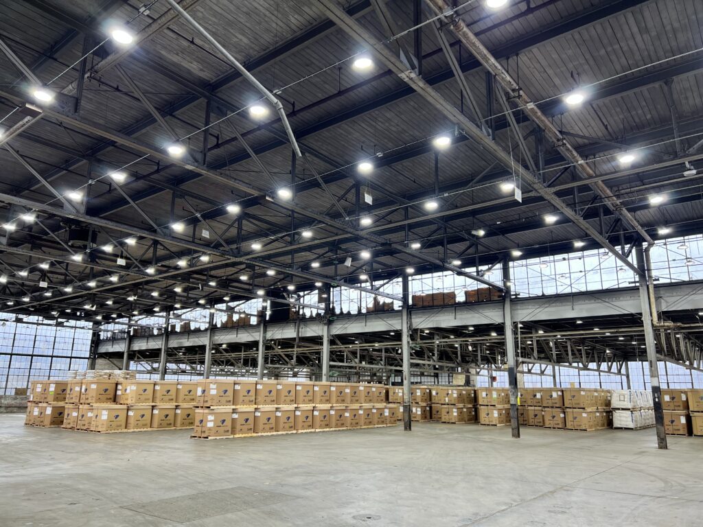 Interior view of a hazardous warehouse in New York City, a key location for shipping logistics, showing neatly stacked red and silver goods under industrial lighting.